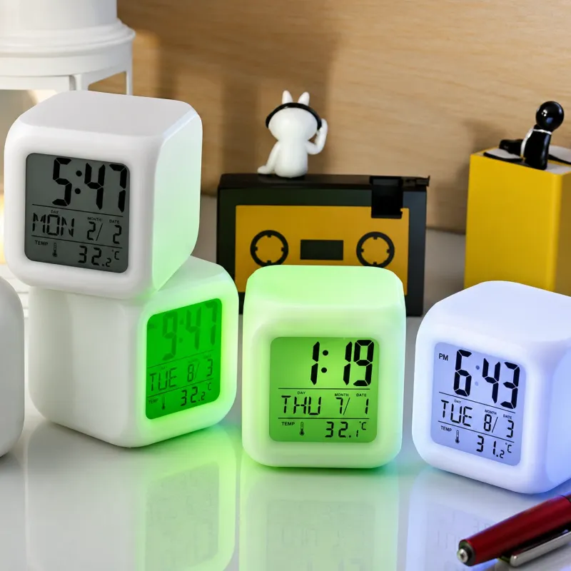 Cube Digital Alarm Clock shown glowing in green and blue backlight colors on a glossy table.
