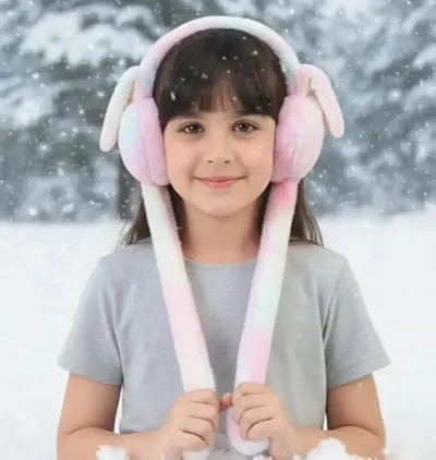 Front view of a young girl wearing light pastel moving bunny ear earmuffs against a snowy forest background.
