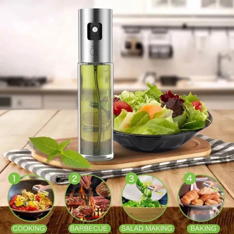 Oil spray bottle for kitchen filled with yellow oil sitting beside a fresh salad bowl on a wooden table.