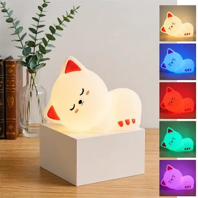 Silicone cat night lamp displaying multiple RGB color options on a white stand next to books.