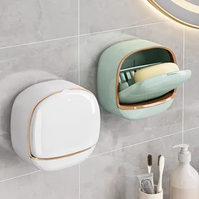 Wall mounted soap box in white and light green with flip covers mounted on a tiled bathroom wall.